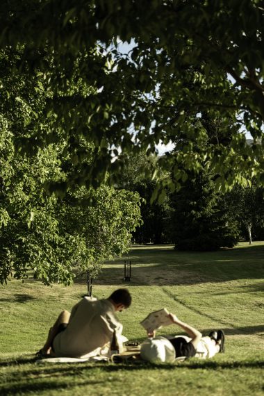 couple lying on a picnic blanket reading in Station Park, Wanaka